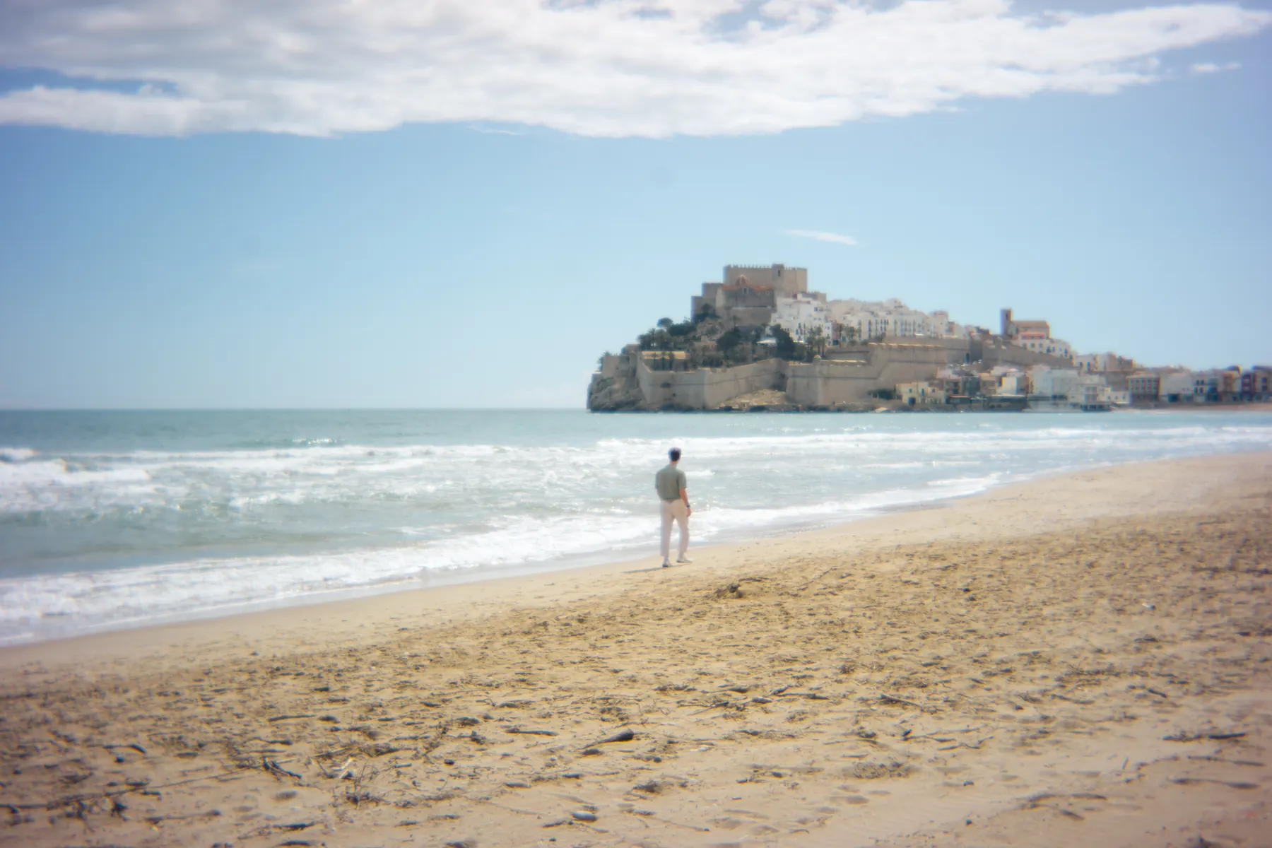 Fortified old town on a rocky headland seen along an empty beach